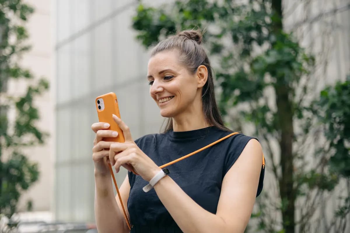 Eine Frau betrachtet ihr Smartphone im Freien.