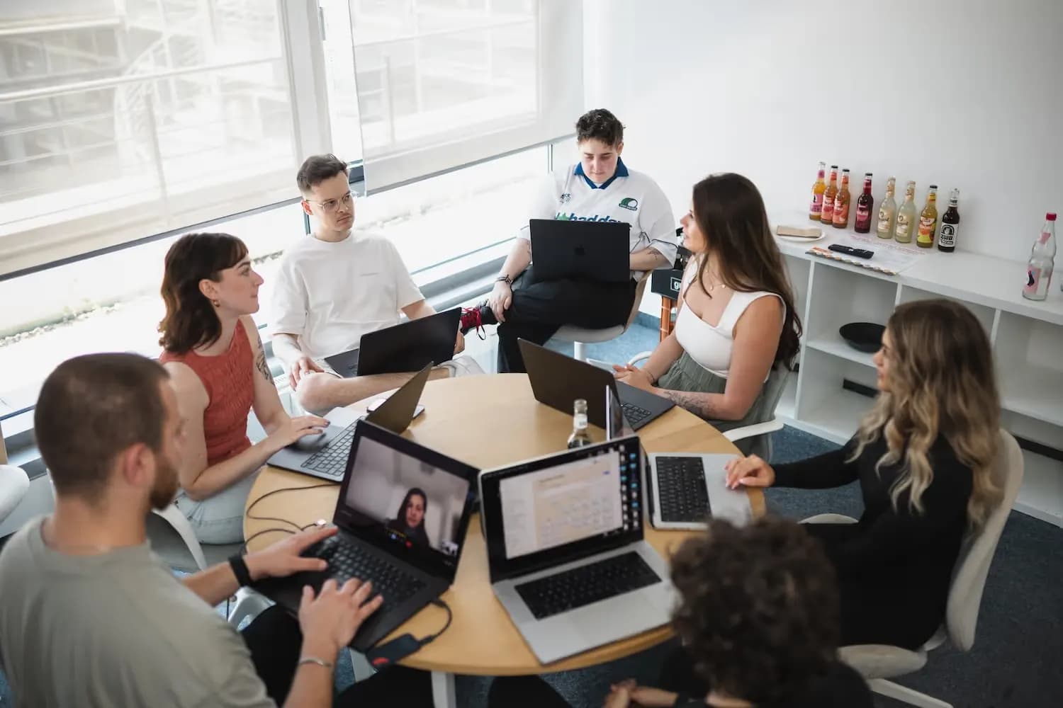 Menschen arbeiten gemeinsam mit Laptops an einem Tisch.
